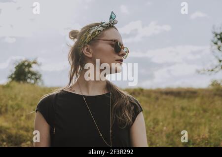 Upper portrait of a woman with a head band and sunglasses looking to the side Stock Photo