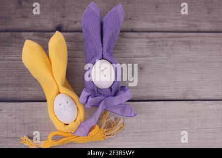 Happy easter concept.Easter holiday table setting with eggs on barn boards. Rubbits from eggs, yellow and purple napkins with bows on wooden backgroun Stock Photo