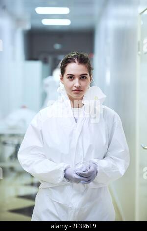 Portrait of young nurse in protective wear looking at camera standing in the corridor at hospital Stock Photo