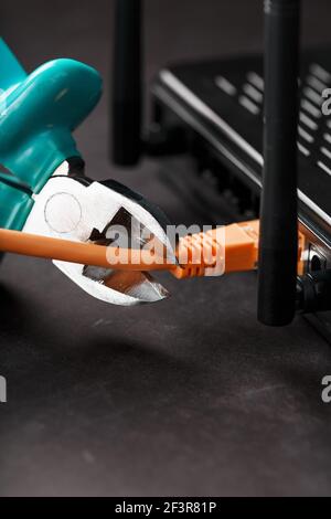 Tearing and cutting with blue wire cutters the network connection of the yellow wire of the Internet connection. Disabling and restricting Internet ac Stock Photo
