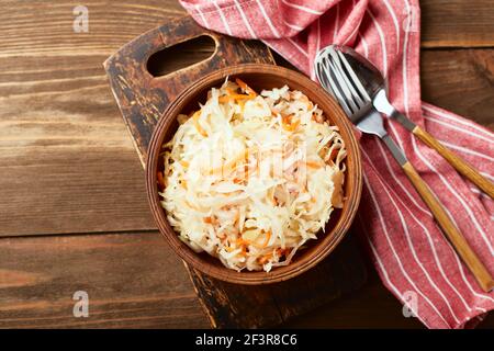 Sauerkraut, fermented cabbage with carrots in bowl on wooden background. Superfoods for support the immune system. Top view, flat lay Stock Photo