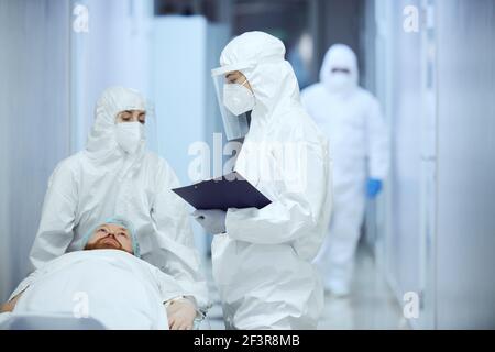 Injured patient lying on gurney with two doctors talking to each other at hospital Stock Photo