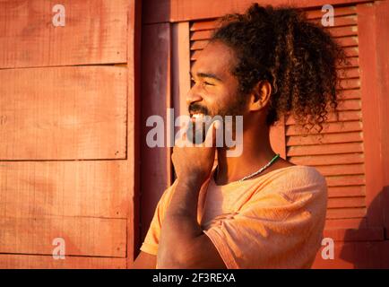 Happy black man. Long curly hair on a young man of Brazilian ethnicity. Concept of hope and joy in pandemic. Stock Photo