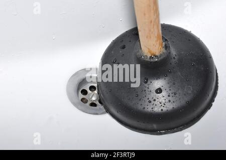 Plunger and sink drain. Pipe cleaning concept. Sanitary engineering work. Focus on sink drain. Stock Photo