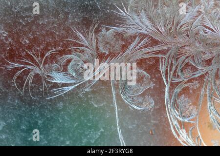 Jack Frost etchings on the window, with a colourful background. Stock Photo