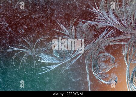 Jack Frost etchings on the window, with a colourful background. Stock Photo