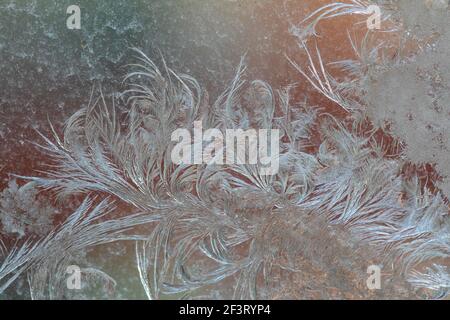 Jack Frost etchings on the window, with a colourful background. Stock Photo