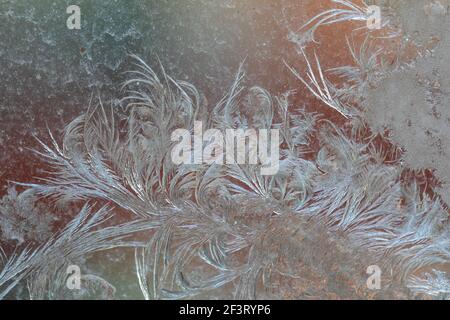 Jack Frost etchings on the window, with a colourful background. Stock Photo
