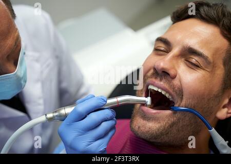 Young man sitting in dental chair and having his teeth treated Stock Photo
