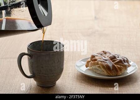 Time for coffee break with cinnamon bun with black coffee is poured into a mug. Photo taken in Sweden. Stock Photo