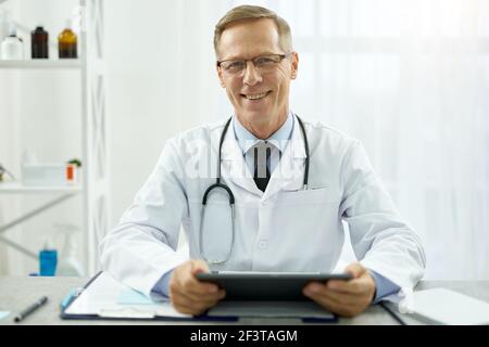 Cheerful male doctor using tablet computer at work Stock Photo