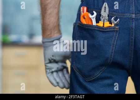 Close up shot of various plumbing hand tools in man's jeans back pocket Stock Photo