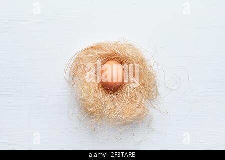Fresh egg on a straw nest on a wooden table. Happy easter concept Stock Photo
