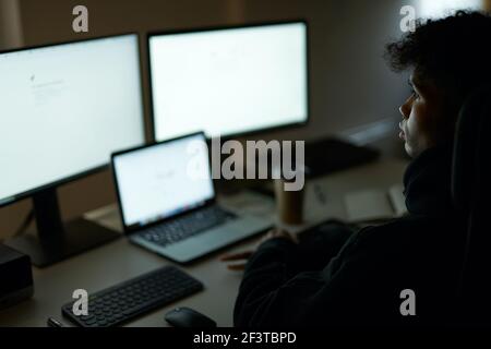 Be busy. Skilled specialist, guy sitting in front of many computer monitors, testing, finishing or debugging software Stock Photo