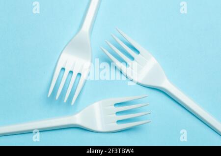 Plastic forks on a blue background. Plastic waste and pollution concept. Stock Photo