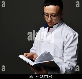 Young man doctor read book. Medicine worker. Healthcare concept on dark