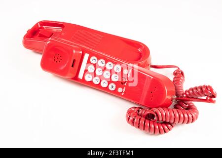 Red analog telephone for making calls. Old electronic accessories used at home and in the office. Light background. Stock Photo