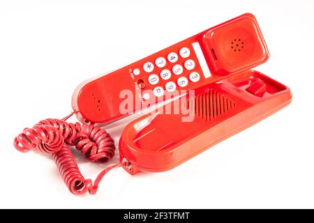 Red analog telephone for making calls. Old electronic accessories used at home and in the office. Light background. Stock Photo