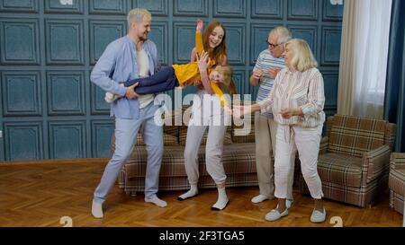 Family members of different generations having fun listening music, dancing crazy in room at home Stock Photo