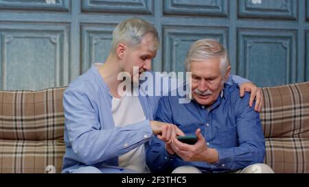 Different male generations family resting, using mobile applications, shopping in online store Stock Photo