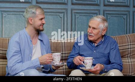 Different male generations family of senior father and adult son or grandson relaxing, drinking tea Stock Photo