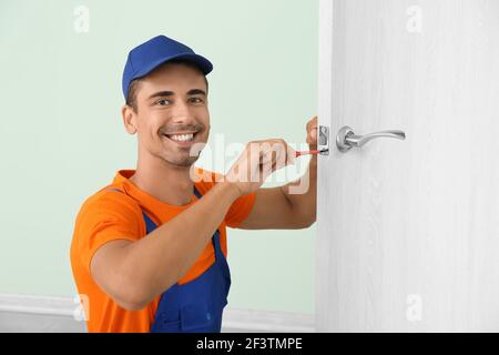 Worker repairing door lock with screwdriver Stock Photo