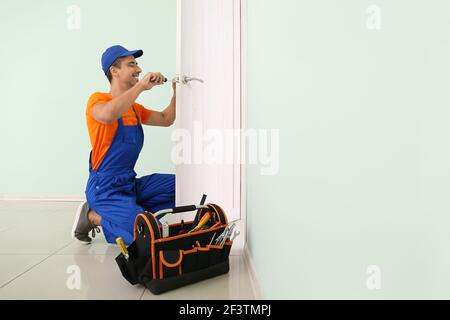 Worker repairing door lock with screwdriver Stock Photo