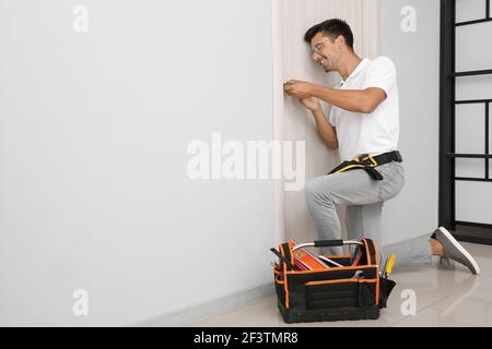 Construction worker repairing door indoors Stock Photo