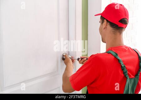 Worker repairing door lock with screwdriver Stock Photo