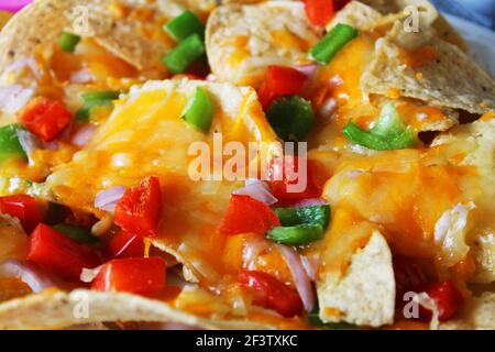 Close-up of a plate of nachos, with cheese, onions, and red and green peppers. Stock Photo