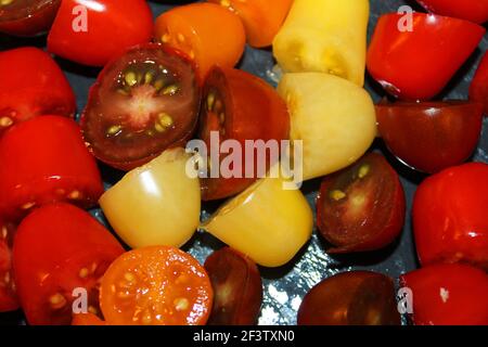 Close-up of multicolored cherry tomatoes sliced, on a stone cutting board. Stock Photo