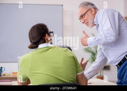 Aged male teacher and young male student in the classroom Stock Photo