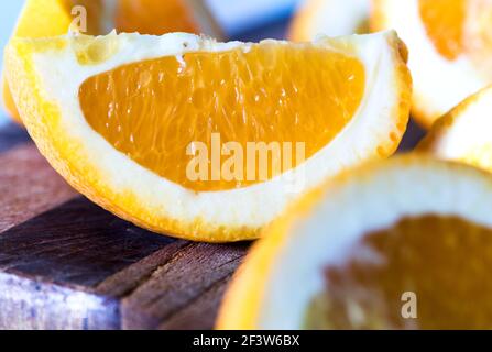 Orange wedges on a kitchen cutting board on blue background Stock Photo