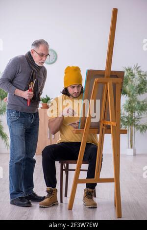 Senior man experienced artist teaching drawing classes to adults ...