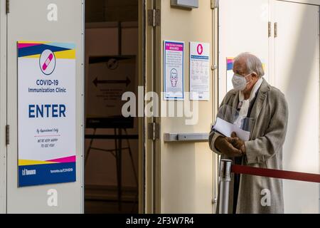 An elderly man wearing a mask waits outside a Metro Convention Centre to receive his first of two COVID-19 vaccine shots.Toronto has launched 'Let's get TO Vaccinated' program to eradicate COVID-19 pandemic. Stock Photo