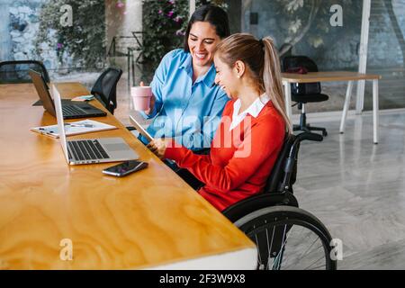 Young latin woman in wheelchair working with computer at workplace or office in Mexico city Stock Photo