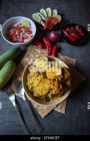 Popular mughlai cuisine biryani in a bowl along with salad condiments Stock Photo