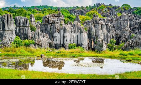 Panorama of Shilin major stone forest with bright fall colors and pond with water reflection in Kunming Yunnan China Stock Photo