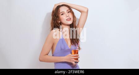 attractive smiling girl drinking soda. Studio shot of stylish young woman in lilac outfit isolated on with background. Stock Photo