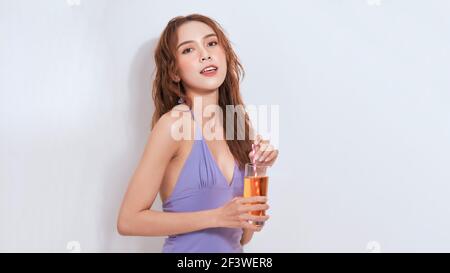 attractive smiling girl drinking soda. Studio shot of stylish young woman in lilac outfit isolated on with background. Stock Photo