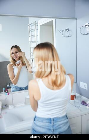 Charming woman applying powder on face in bathroom Stock Photo