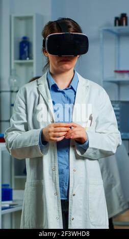 Laboratory doctor experiencing virtual reality using vr goggles in medical neurological research lab. Physician therapist using medical innovation equipment device glasses, analysing brain scan Stock Photo