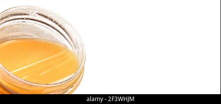Glass jar with amber coloured honey, closeup detail, isolated on white background, space for text right side Stock Photo