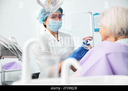 Young woman dentist moving probe during teeth model demonstration Stock Photo