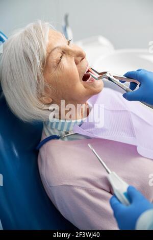 Doctor is removing upper tooth with forceps Stock Photo