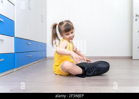 Little girl trying on her daddy's big boots Stock Photo