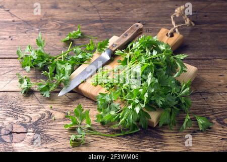 Bunch of fresh organic parsley on a cutting board on a wooden table, selective focus, rustic style Stock Photo