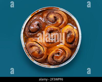 freshly baked cinnamon rolls covered with caramel sauce on blue background, top view Stock Photo