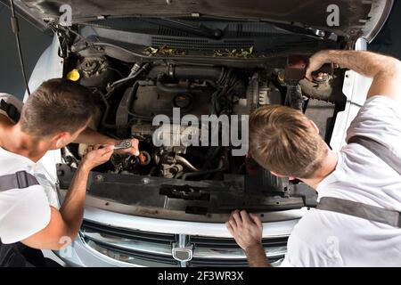 Working together on a car engine in workshop Stock Photo