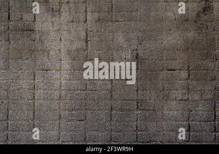The brick wall is covered with dark gray cement plaster. Rough grout surface. Abstract background. Stock Photo